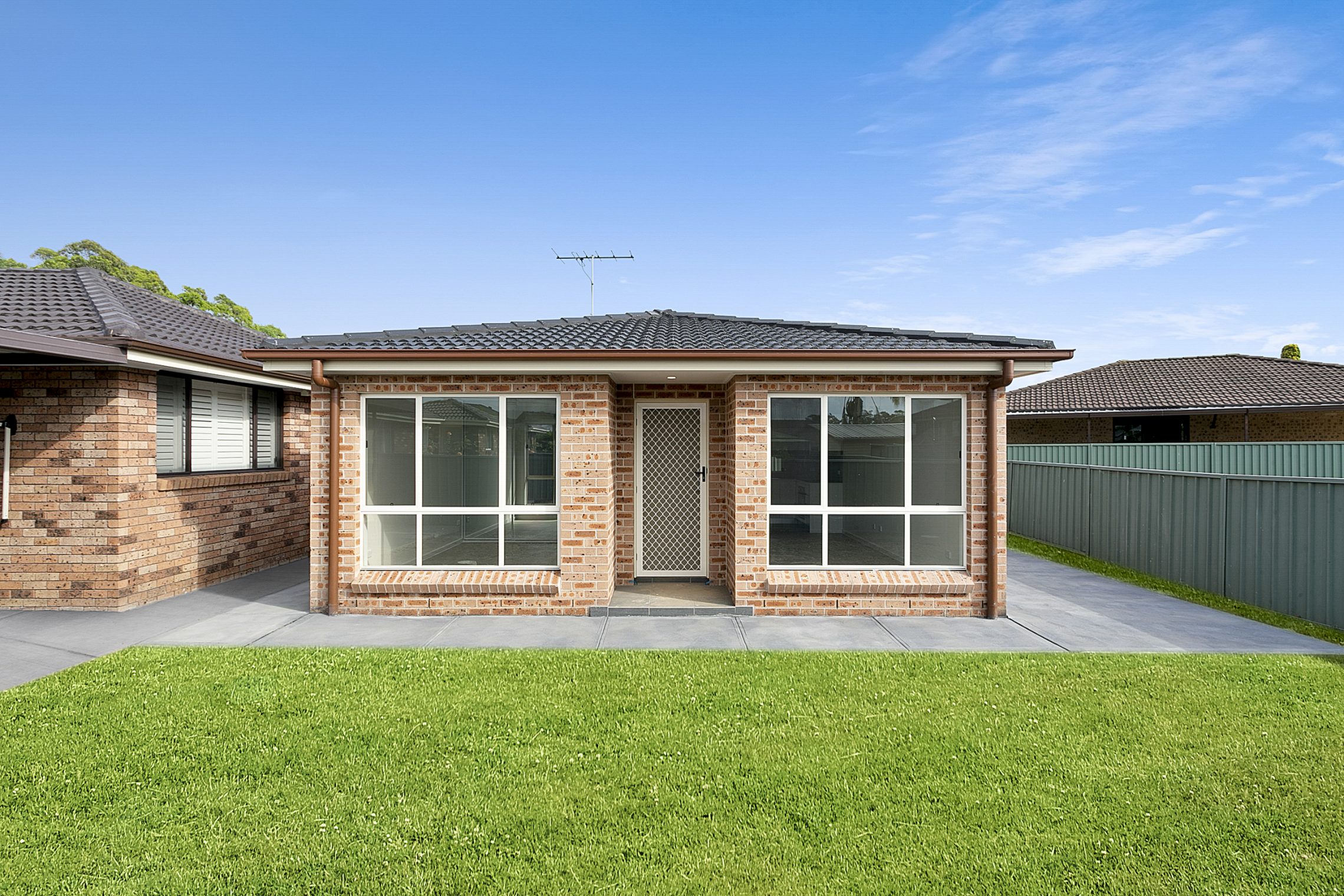 Backyard of small brick granny flat with floor to ceiling windows