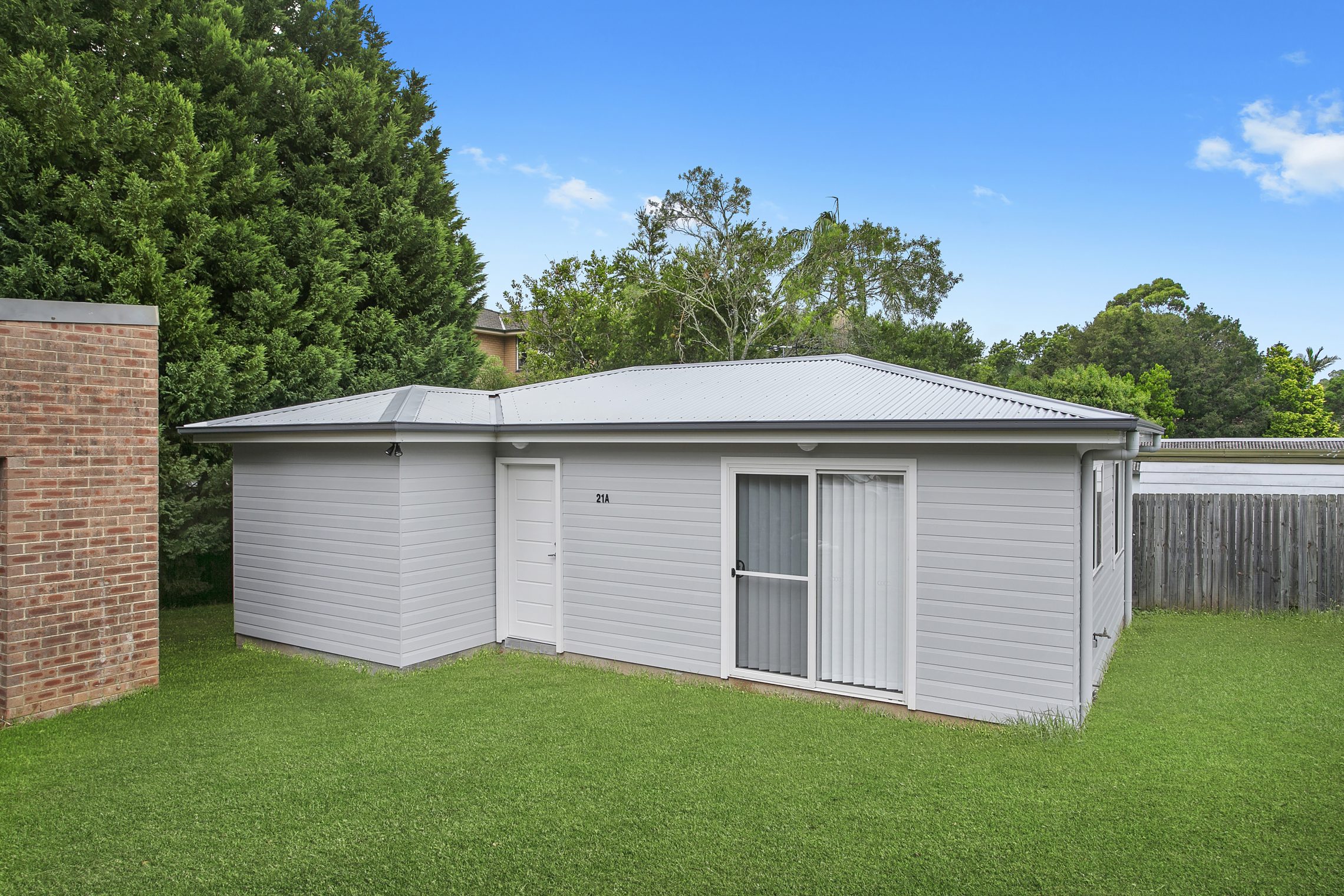 Small grass surrounded granny flat with entry door and sliding glass door