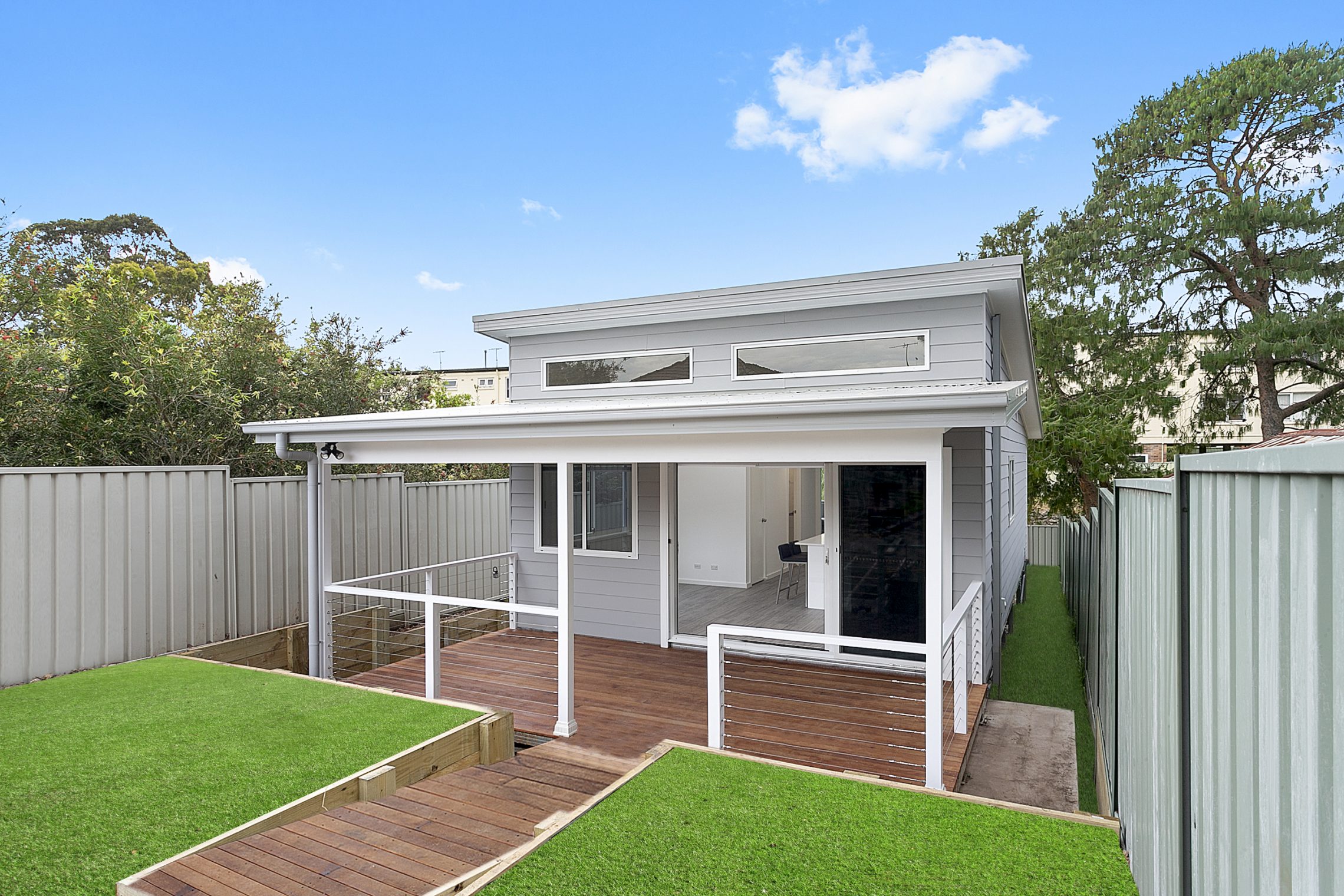 Wooden walkway leading to large wooden deck and sliding door entry to granny flat