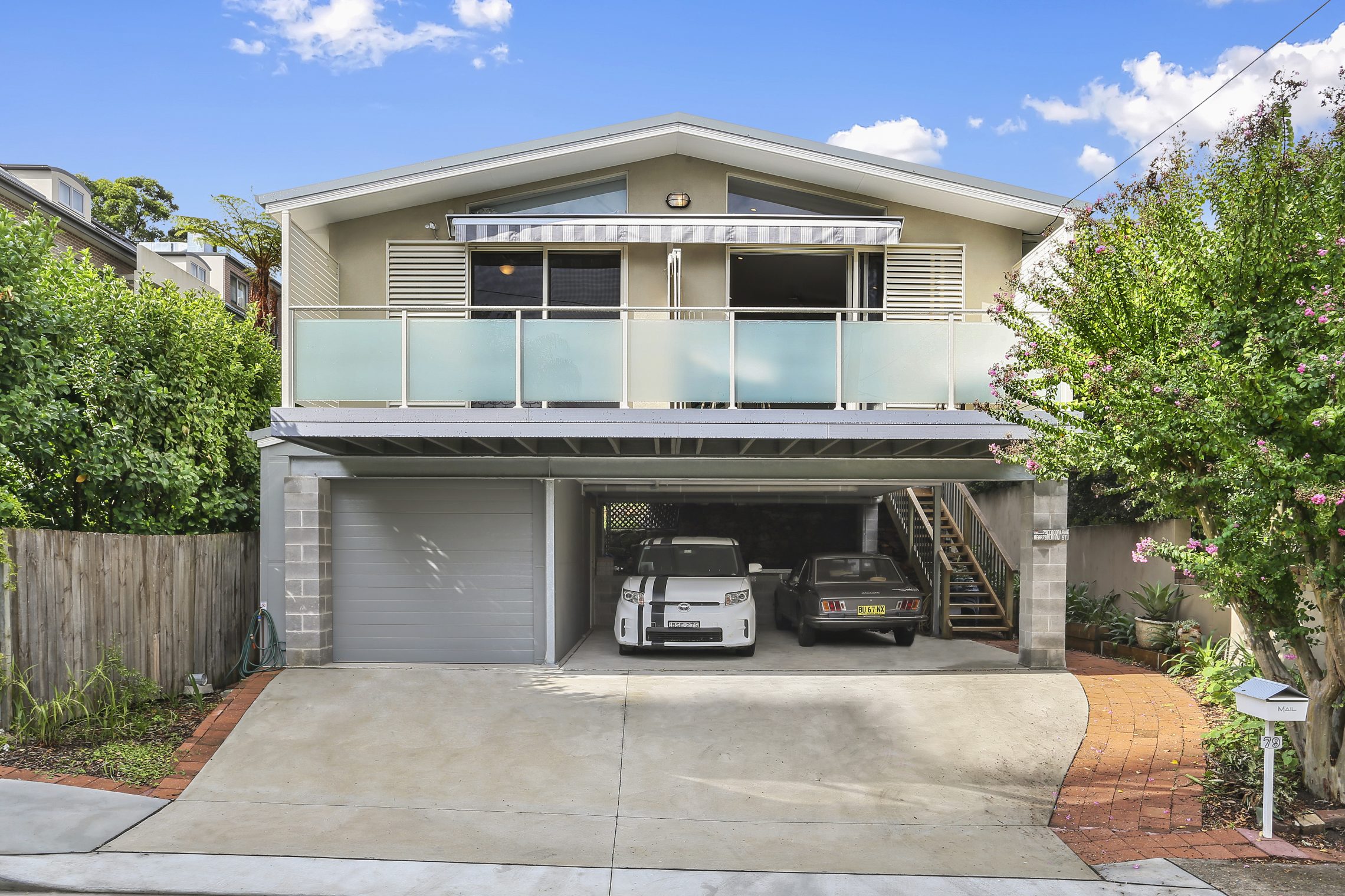 The front entry to a two storey home with balcony, garage and covered car park