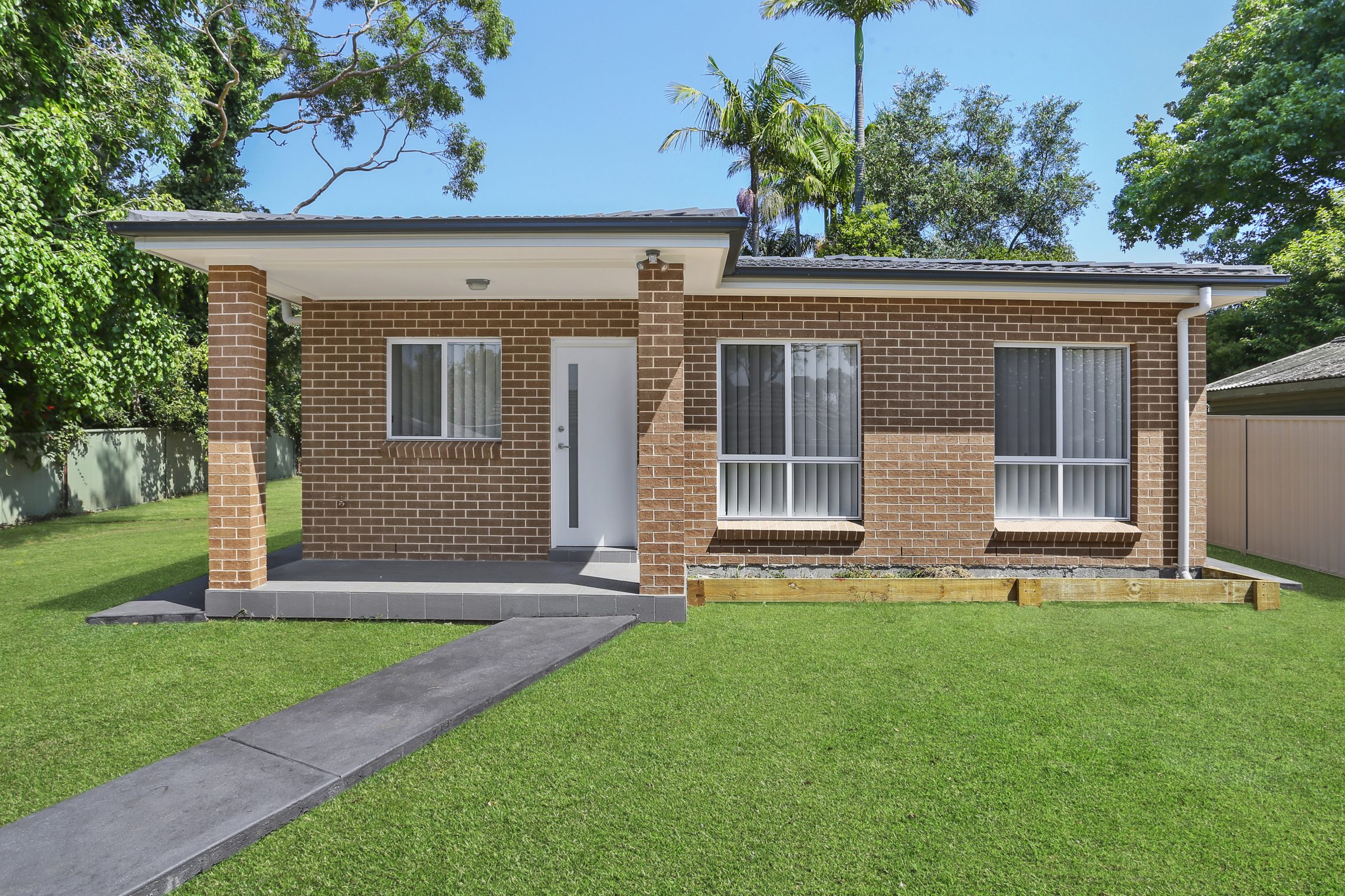 Brick granny flat with cement walkway and covered cement patio entry point