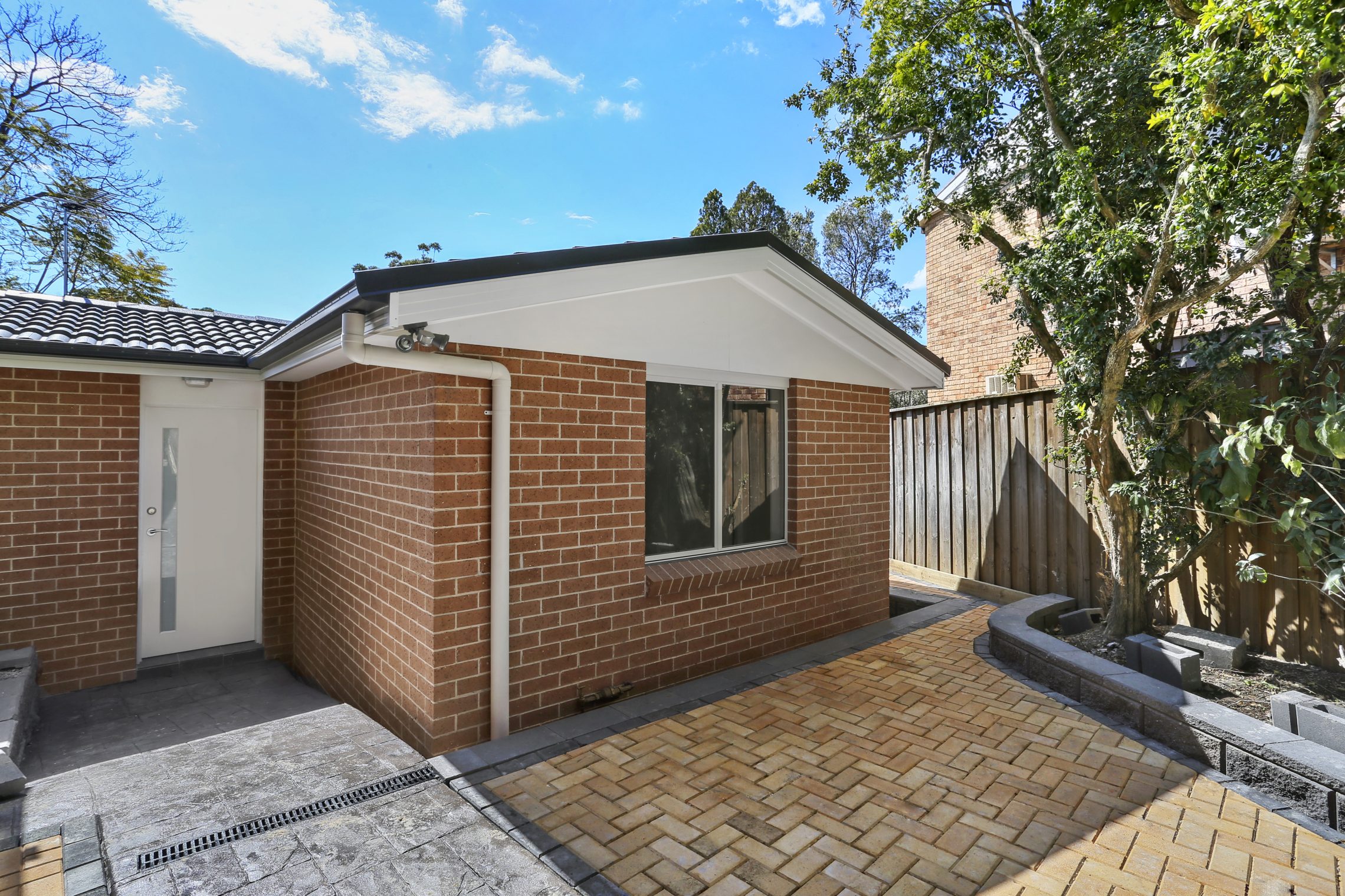 Small brick granny flat with small brick courtyard next to entry