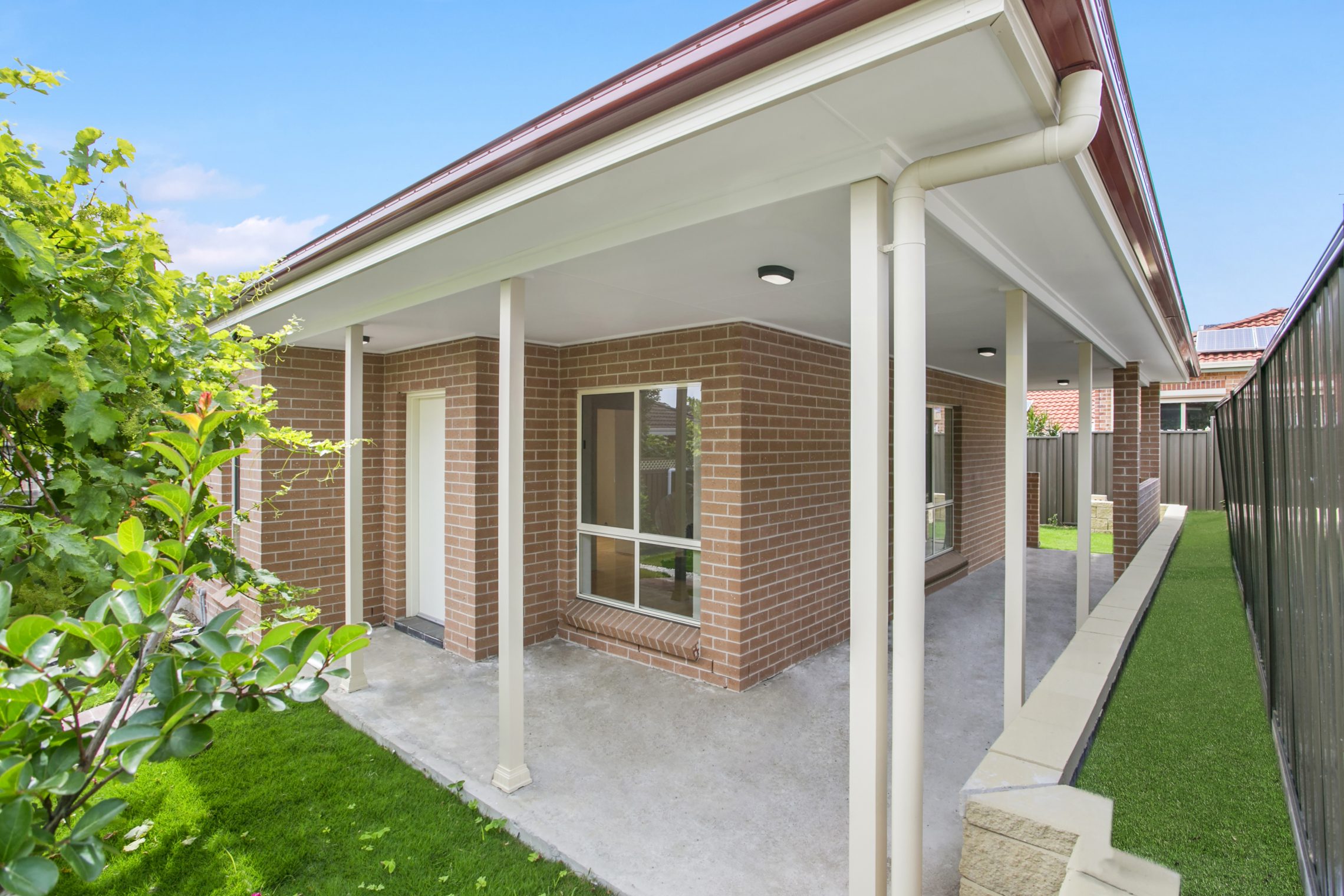 Granny flat with roof extending above front and side cement walkway