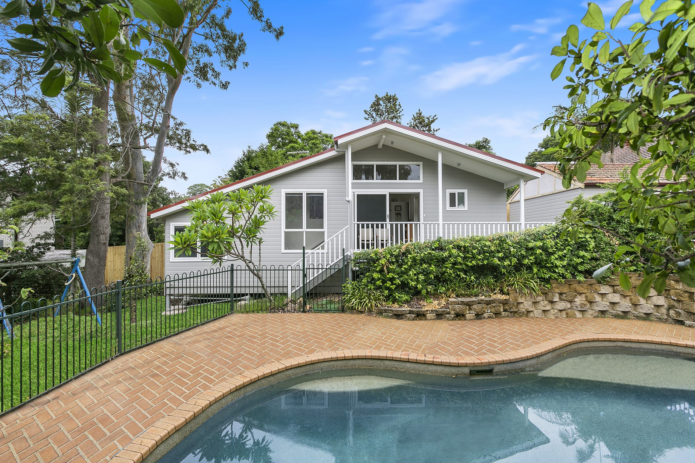 A brick courtyard with a built in pool and the back windows of home overlooking the area