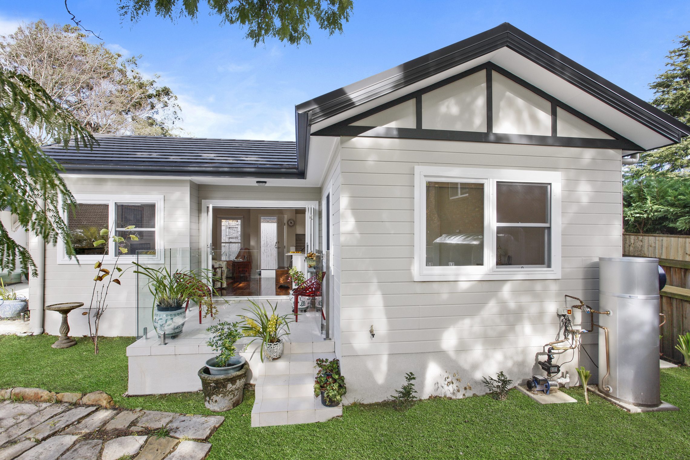 Four steps leading up to small patio and quaint white granny flat