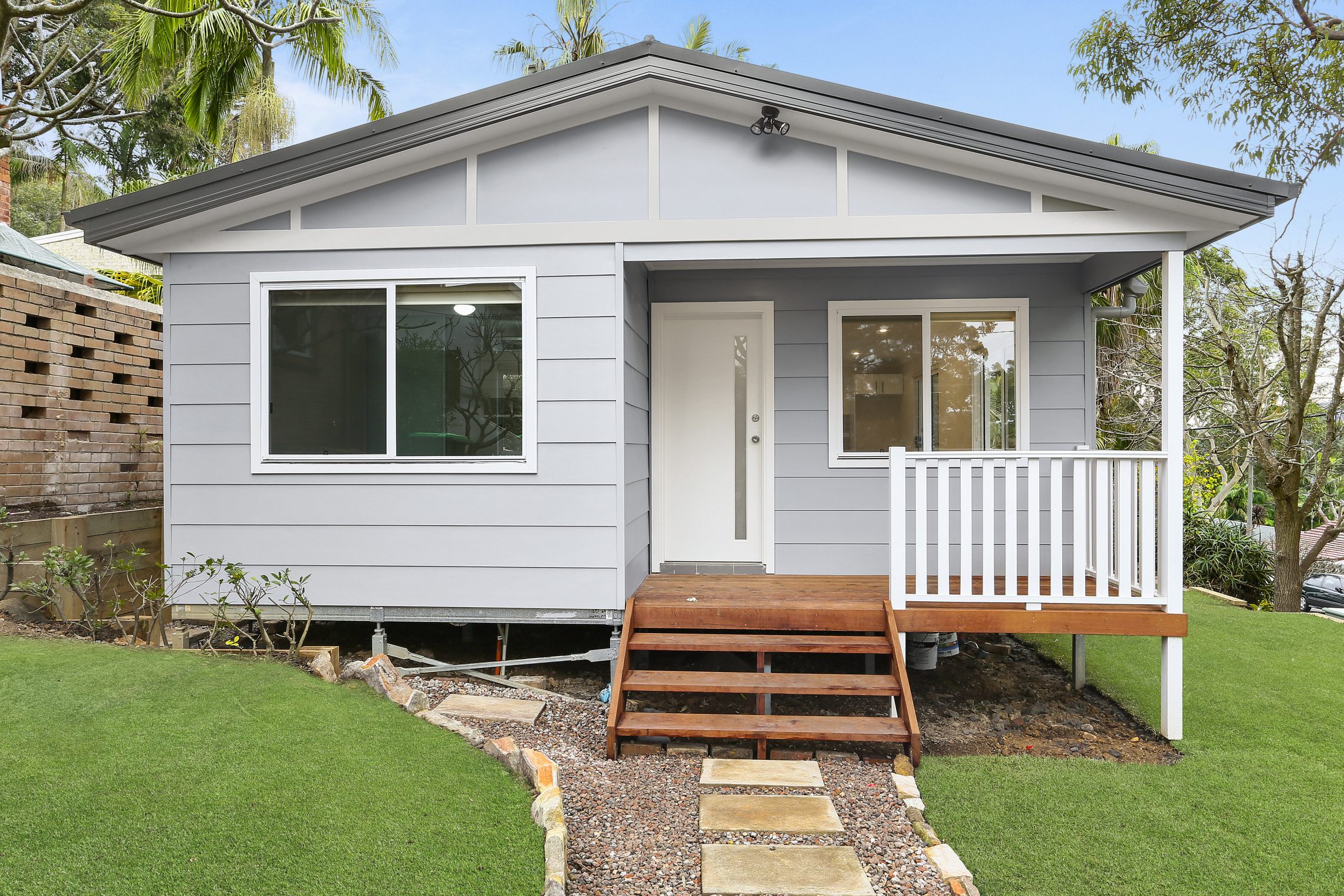 Quaint blue granny flat with small wooden elevated porch to entry