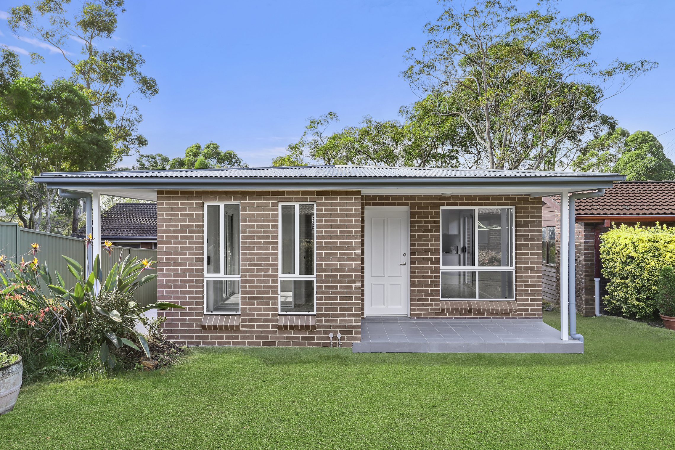 Small brick granny flat with covered entry and small patio