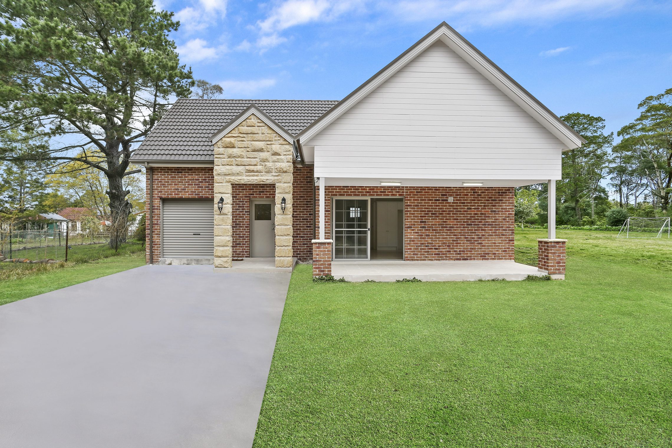 Large driveway leading to single car garage and stone covered entry point