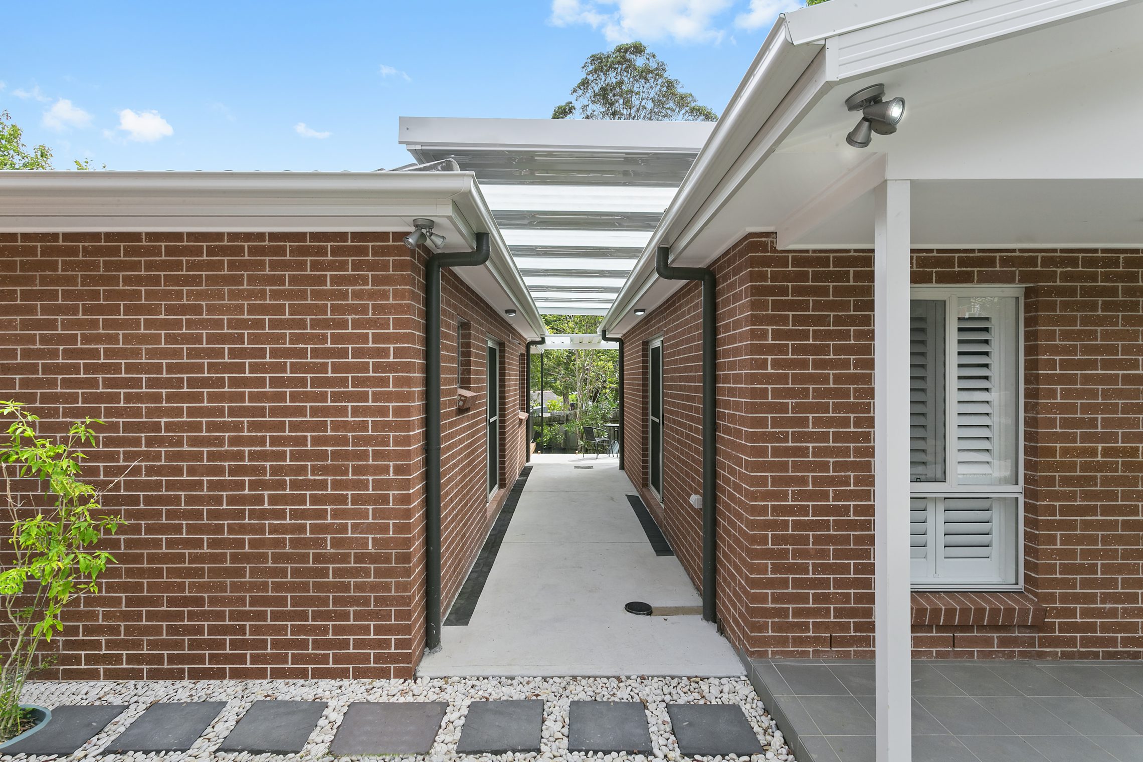 A paved and sheltered corridor created between two brick granny flats