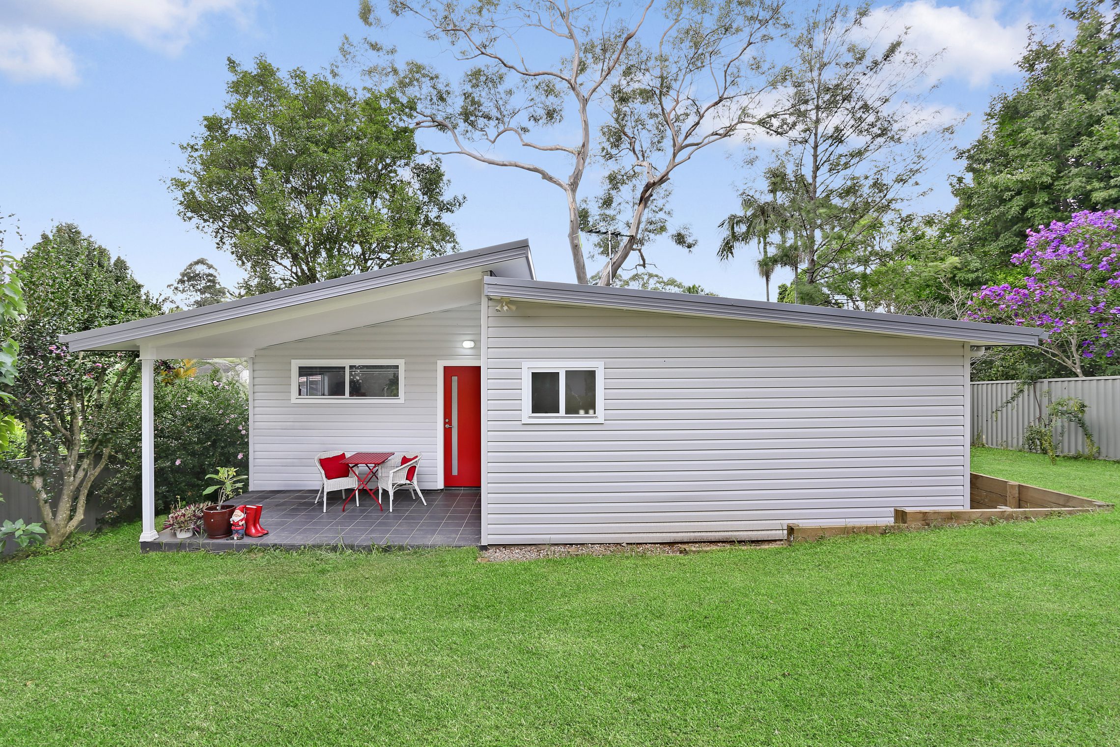 Sloped roof granny flat with red door and small front patio