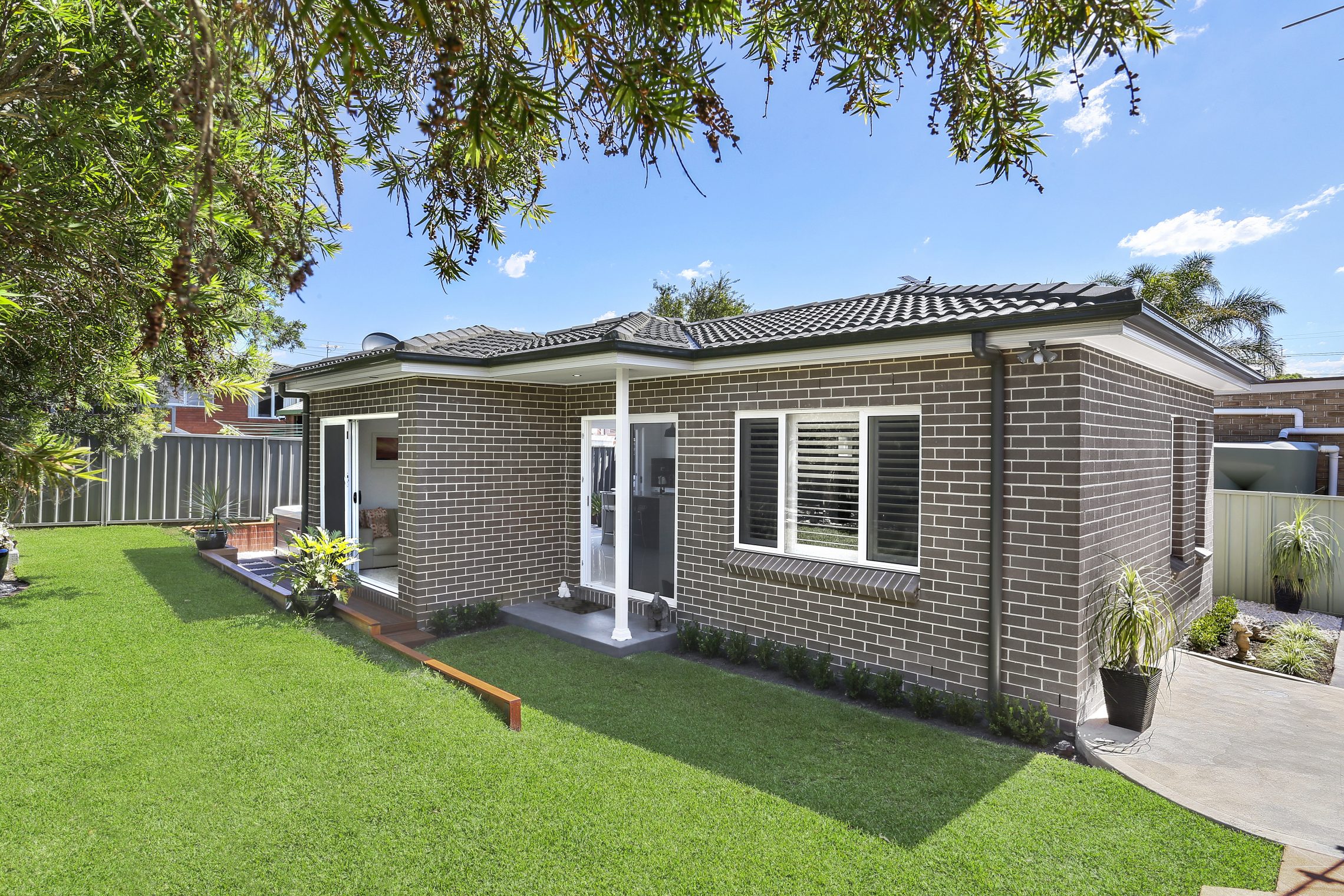 Grassy lawn with two entry points into granny flat on one side of the building