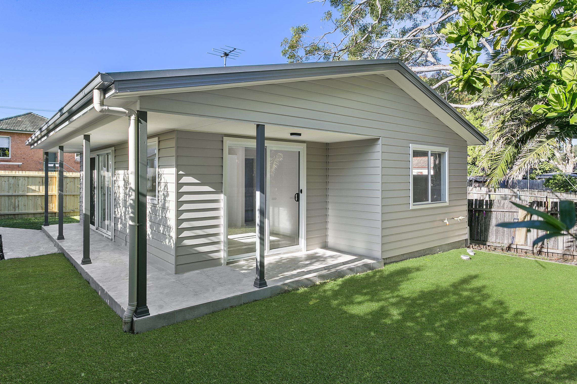 Sliding glass door entry to granny flat surrounded by grass