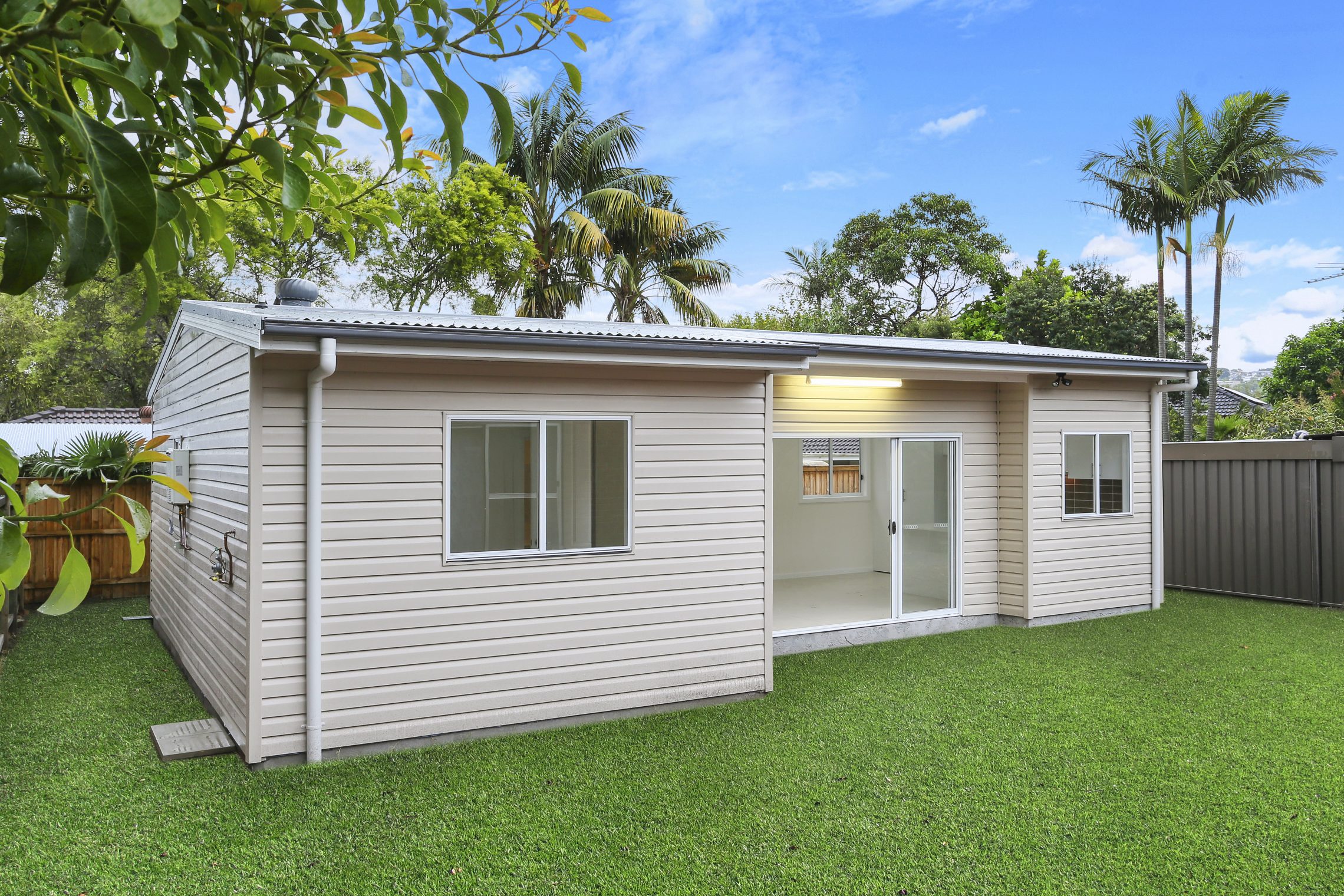 Small granny flat surrounded by grass with sliding door entry