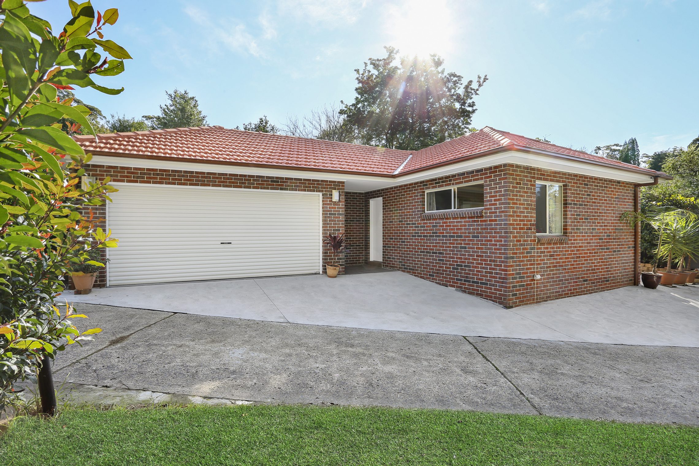 Driveway leading to brick granny flat with two-car garage and covered entry