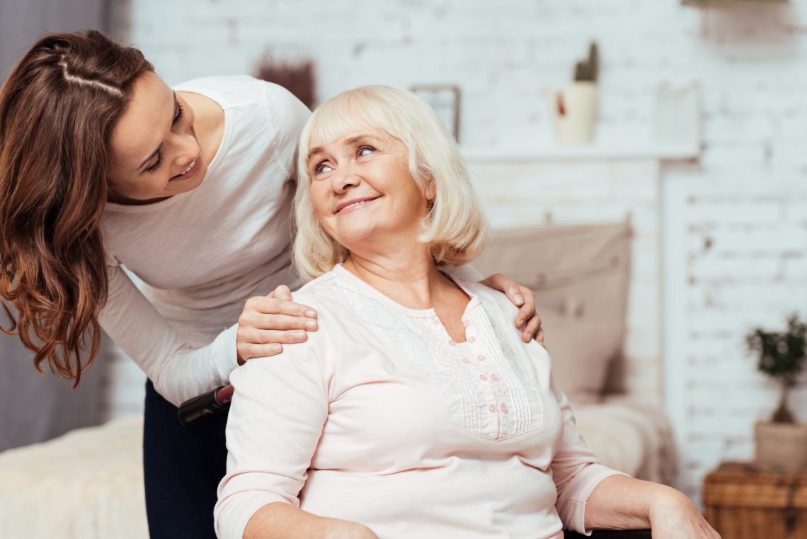 young woman smiling at older woman in chair