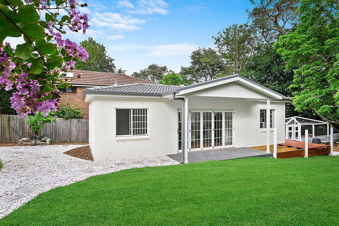 Stone step-way leading to covered stone patio in front of lattice door entry point to granny flat