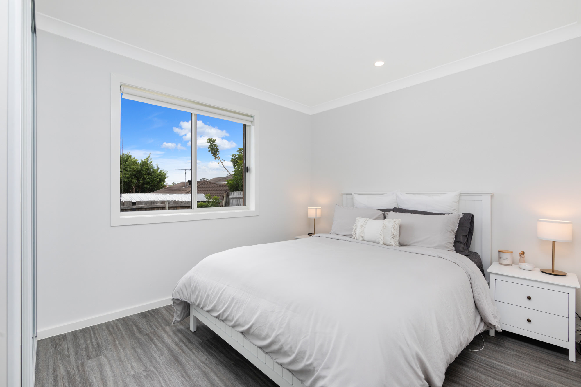 queen bed in a bedroom with a window and soft clean lighting