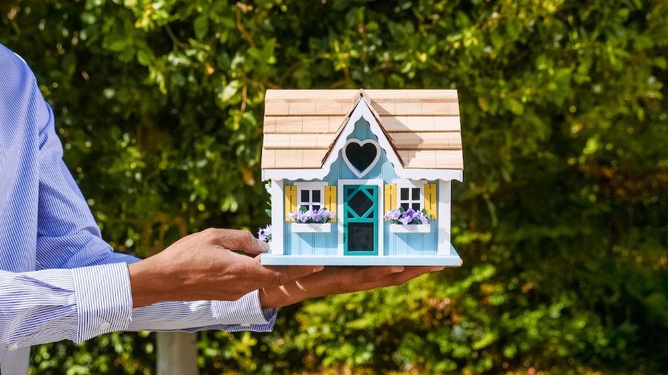 Hand holding tiny home with heart shaped window