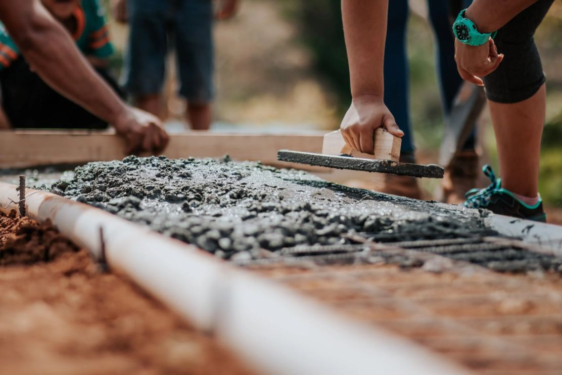 Two hands laying down wet concrete